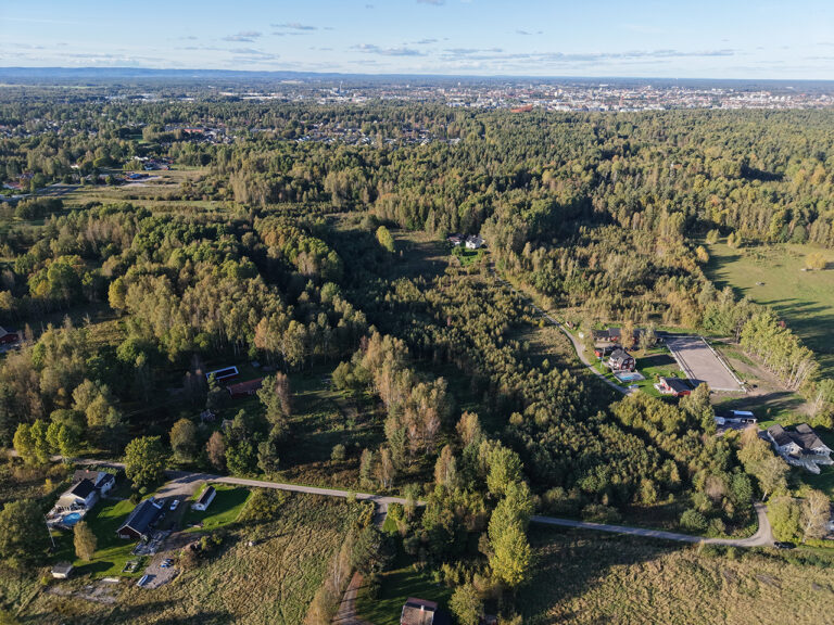 Flygbild över Bondsätter i södra Örebro med skog, bebyggelse och stadsvy i bakgrunden.